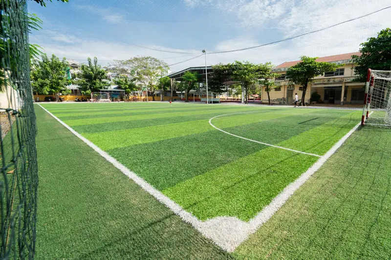 Thuê Sân Bóng Cỏ Nhân Tạo: Kiến Thức Chuyên Sâu 2026 Từ A-Z 2 thuê sân bóng cỏ nhân tạo nhóm cầu thủ đang vui vẻ trên sân bóng nhân tạo vào buổi tối